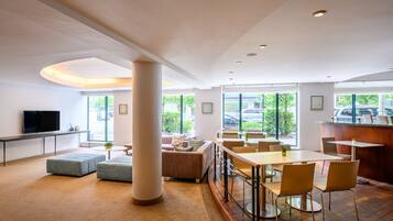 Un hall d’hôtel moderne doté d’un grand espace salon, d’un bar et d’un téléviseur.
