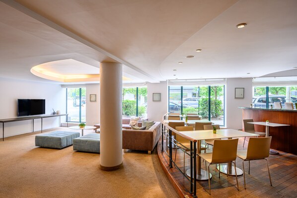 Un moderno vestíbulo de hotel con un amplio espacio de descanso, un bar y una televisión.
