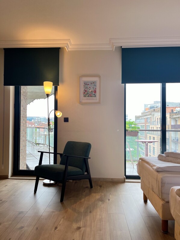 Una habitación moderna con una cama, una silla, una mesa y un gran ventanal con vistas a la ciudad.