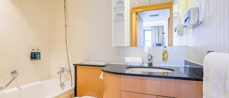 Un baño moderno con bañera, inodoro, lavabo y un espejo grande.