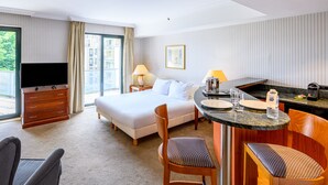 A hotel room with a bed, a desk with a chair, a TV, and a window with curtains. - B-aparthotel Ambiorix (Brussels)