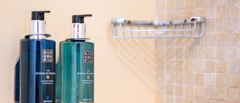 Two bottles of shampoo and conditioner on a wall-mounted rack in a bathroom.