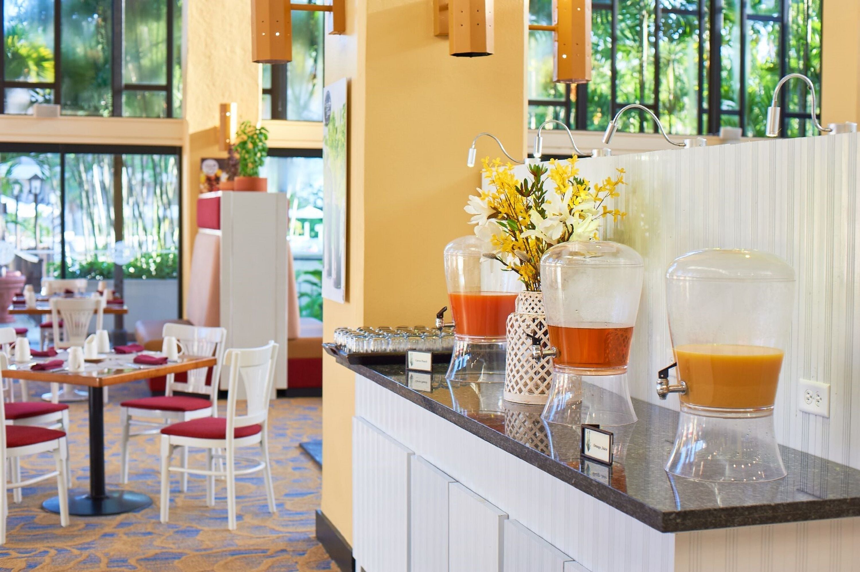 A hotel reception area with a counter displaying various beverages and a vase of flowers.