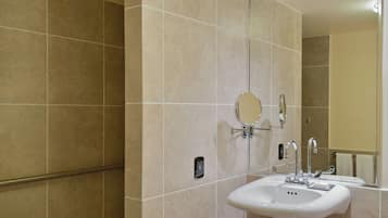Une salle de bain avec des carreaux de couleur beige, un lavabo blanc, un miroir et un porte-serviettes.