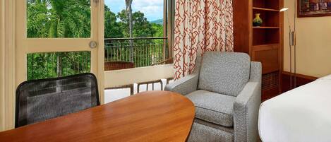 A room with a balcony, a sofa, a table, and a lamp.