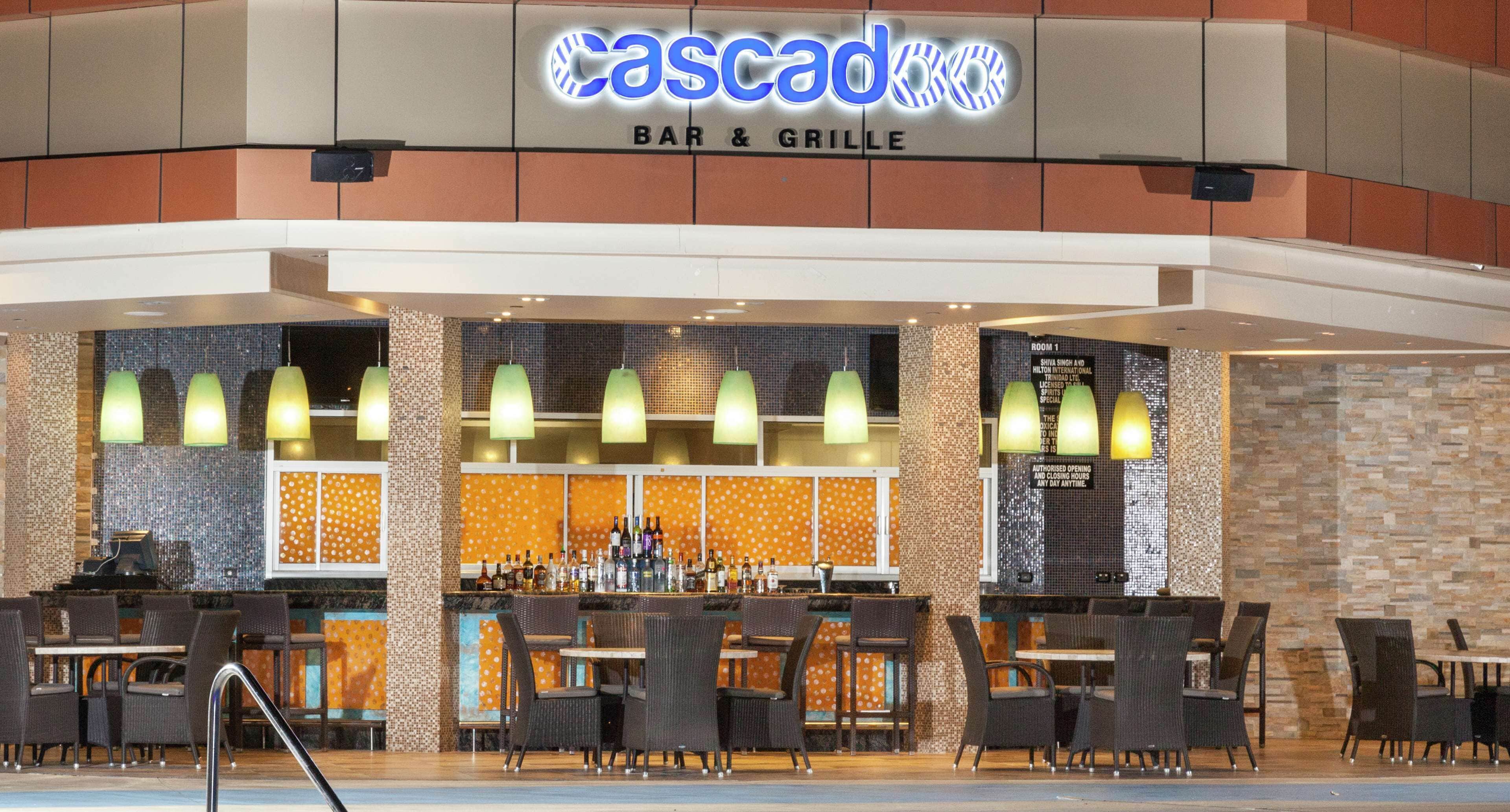 A bar and grill named 'Cascado' with a tiled wall, multiple hanging lights, and outdoor seating.