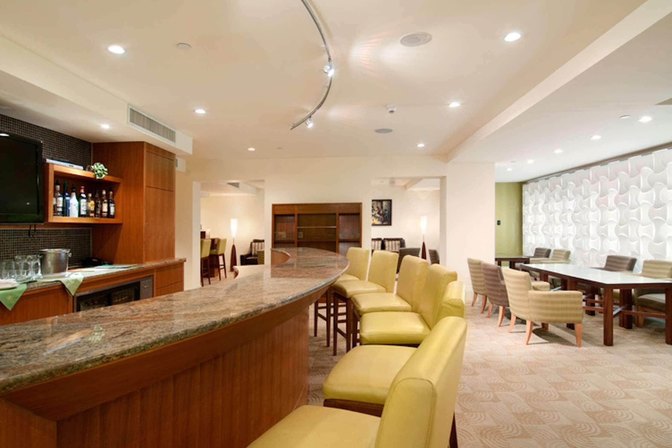 Un moderno vestíbulo de hotel con zona de bar, asientos y una mesa de conferencias.