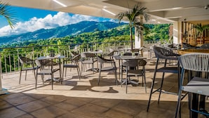 A terrace with outdoor seating and a view of a mountainous landscape. - Hilton Trinidad & Conference Centre (Port of Spain)