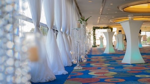 A hotel corridor with a colorful carpet, white drapes, and decorative columns with lights. - Hilton Trinidad & Conference Centre (Port of Spain)