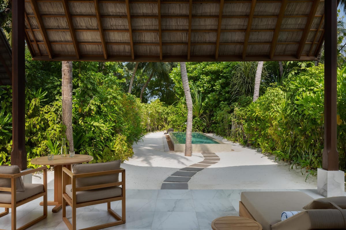 Uma área externa coberta com piscina, espreguiçadeiras e uma mesa.
