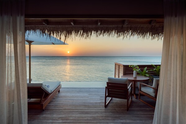A wooden deck with a view of the ocean at sunset.