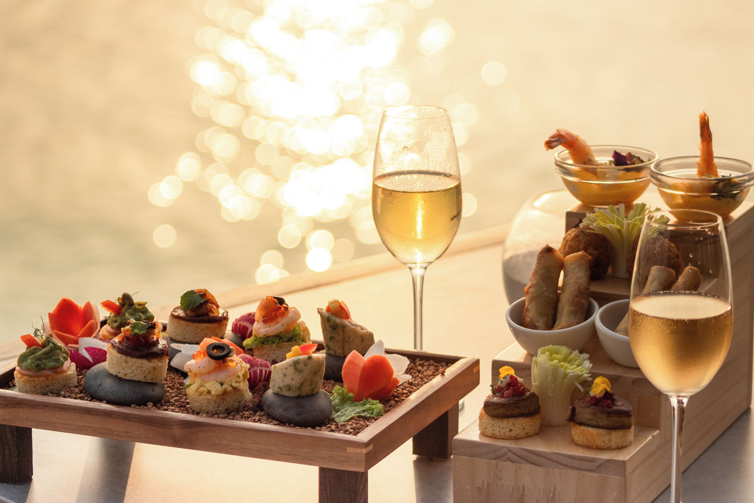 Una mesa con varios aperitivos y una copa de vino blanco.