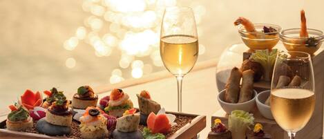 Una mesa con varios aperitivos y una copa de vino blanco.