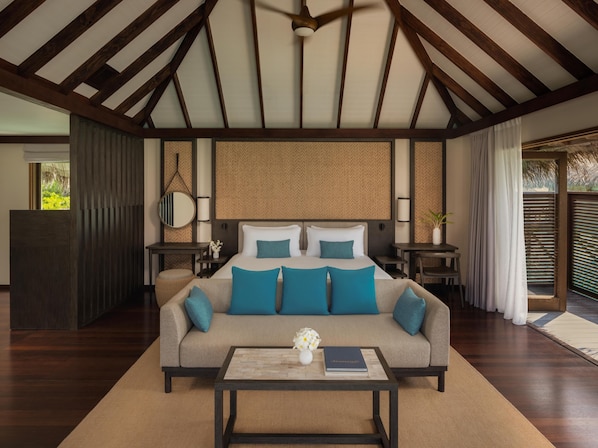 A bedroom with a large bed, a sofa, a coffee table, and a ceiling fan. - Conrad Maldives Rangali Island (Rangalifinolhu)