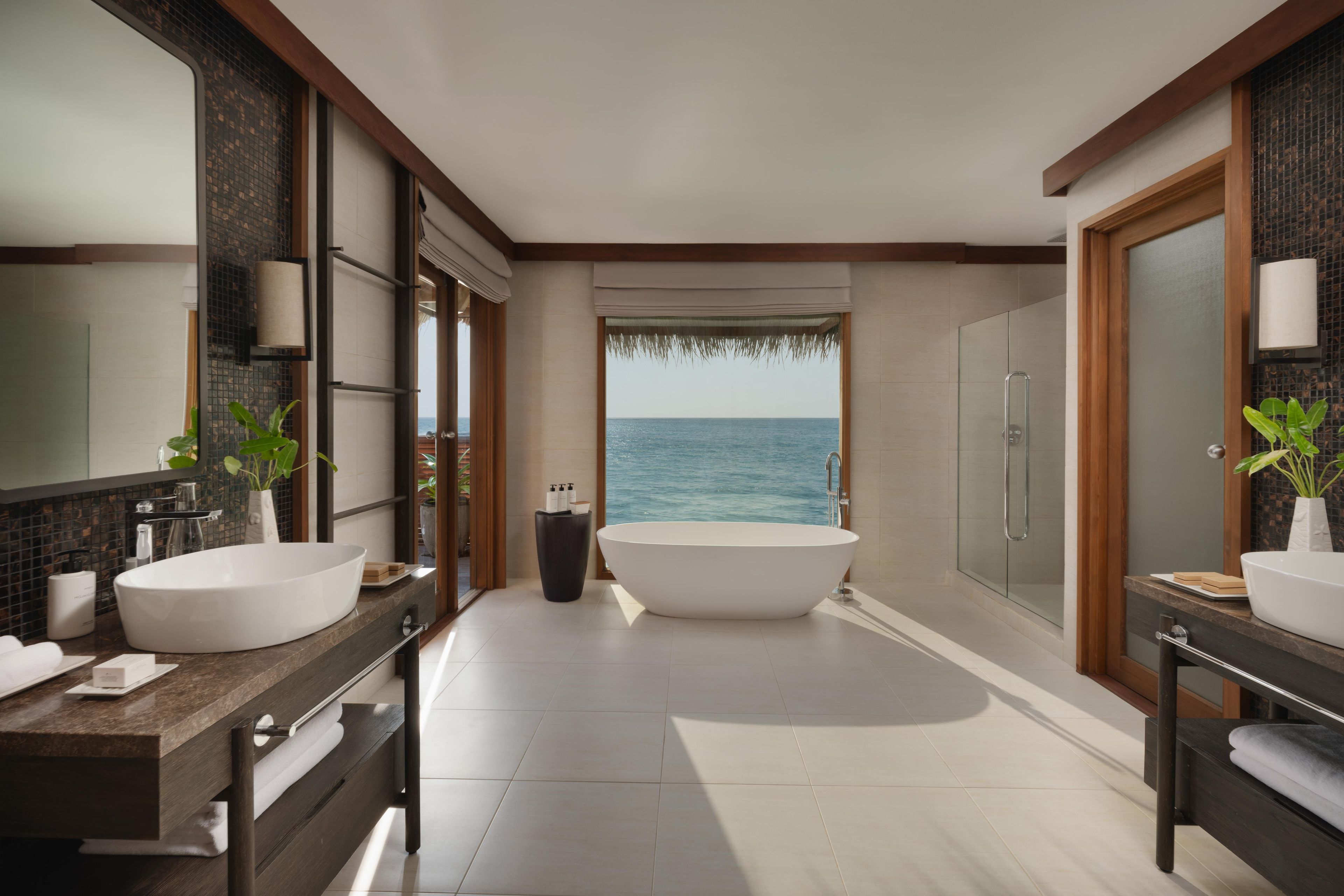 A modern bathroom with two sinks, a large bathtub, and a glass-enclosed shower.