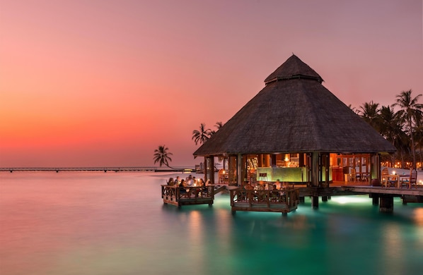 A thatched-roof overwater bungalow with a pool, overlooking calm waters at sunset. - Conrad Maldives Rangali Island (Rangalifinolhu)