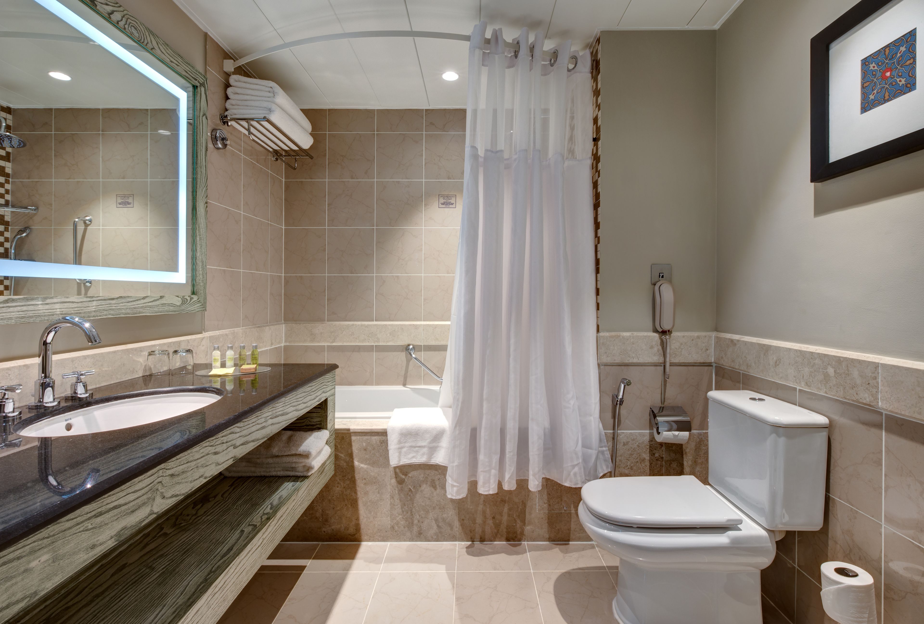 Un baño moderno con lavamanos, espejo, bañera, inodoro y cortina de ducha.