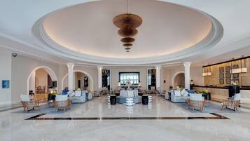 A spacious lobby with a central seating area, multiple columns, and a high ceiling with a unique light fixture.