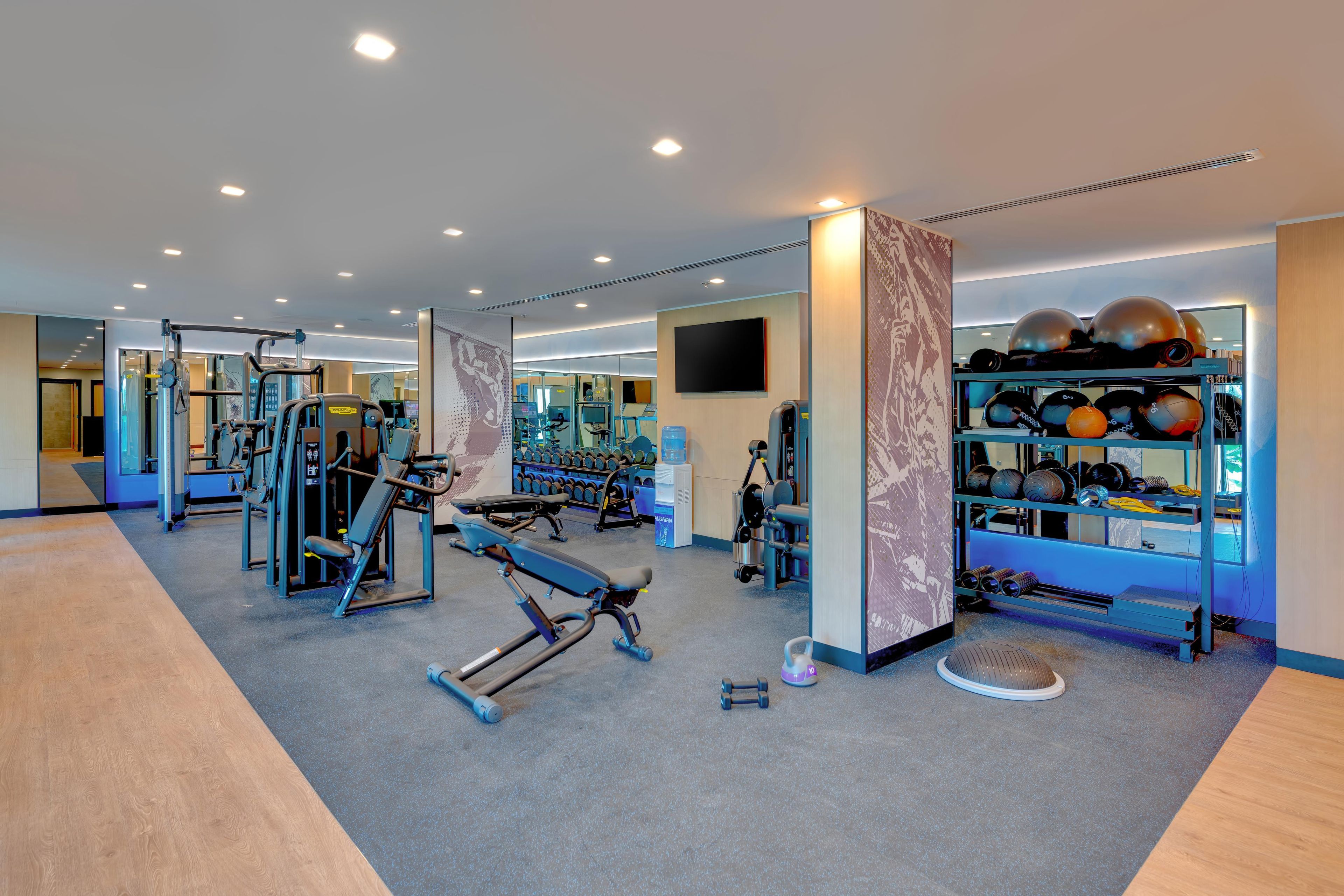 A modern gym with various exercise equipment, including weight machines and free weights.