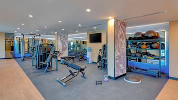 A modern gym with various exercise equipment, including weight machines and free weights.