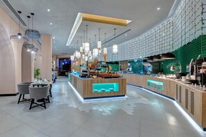 A modern hotel lobby with a central reception desk, seating area, and decorative lighting.