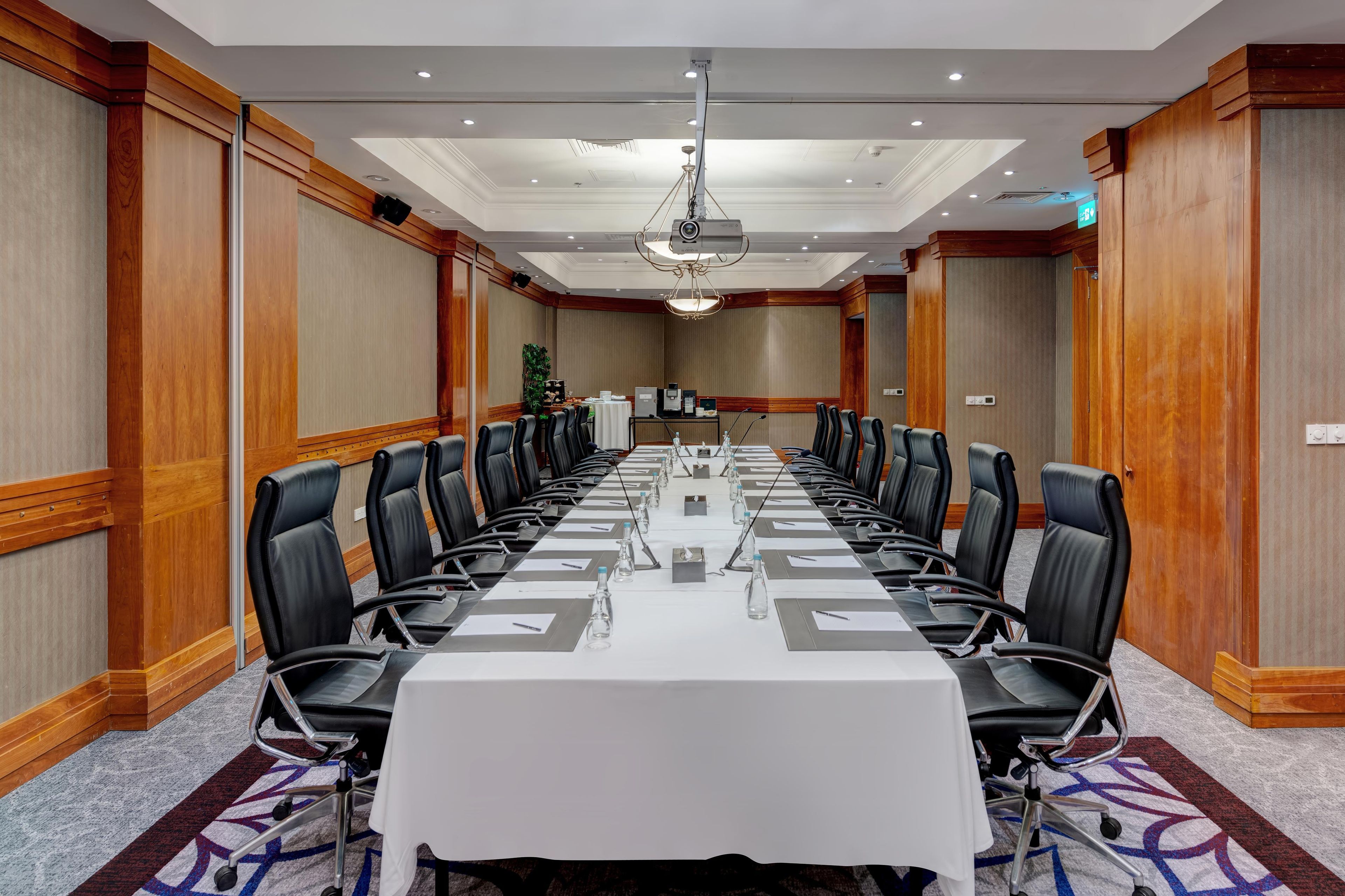 A conference room with a long table, multiple chairs, and a projector.