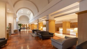 A spacious lobby with a high ceiling, a central seating area with sofas, and a reception desk.