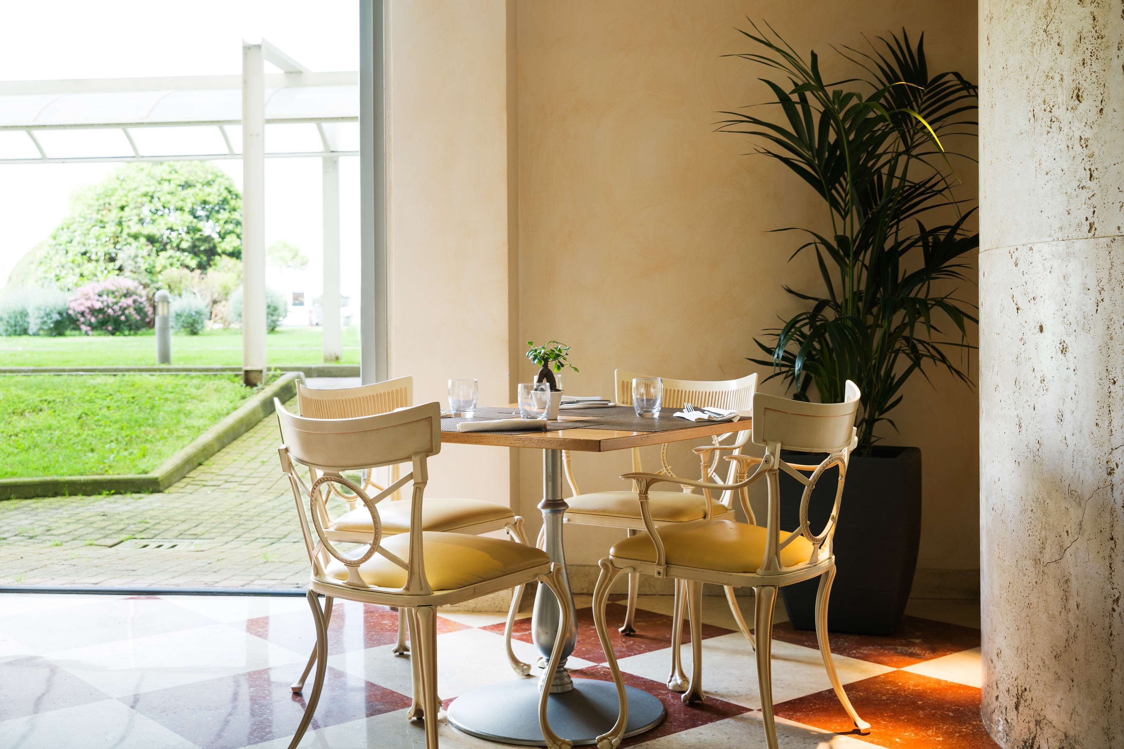 A dining area with a round table, four chairs, and a potted plant.