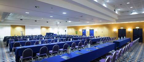 A conference room with rows of tables and chairs, equipped with water bottles and nameplates.