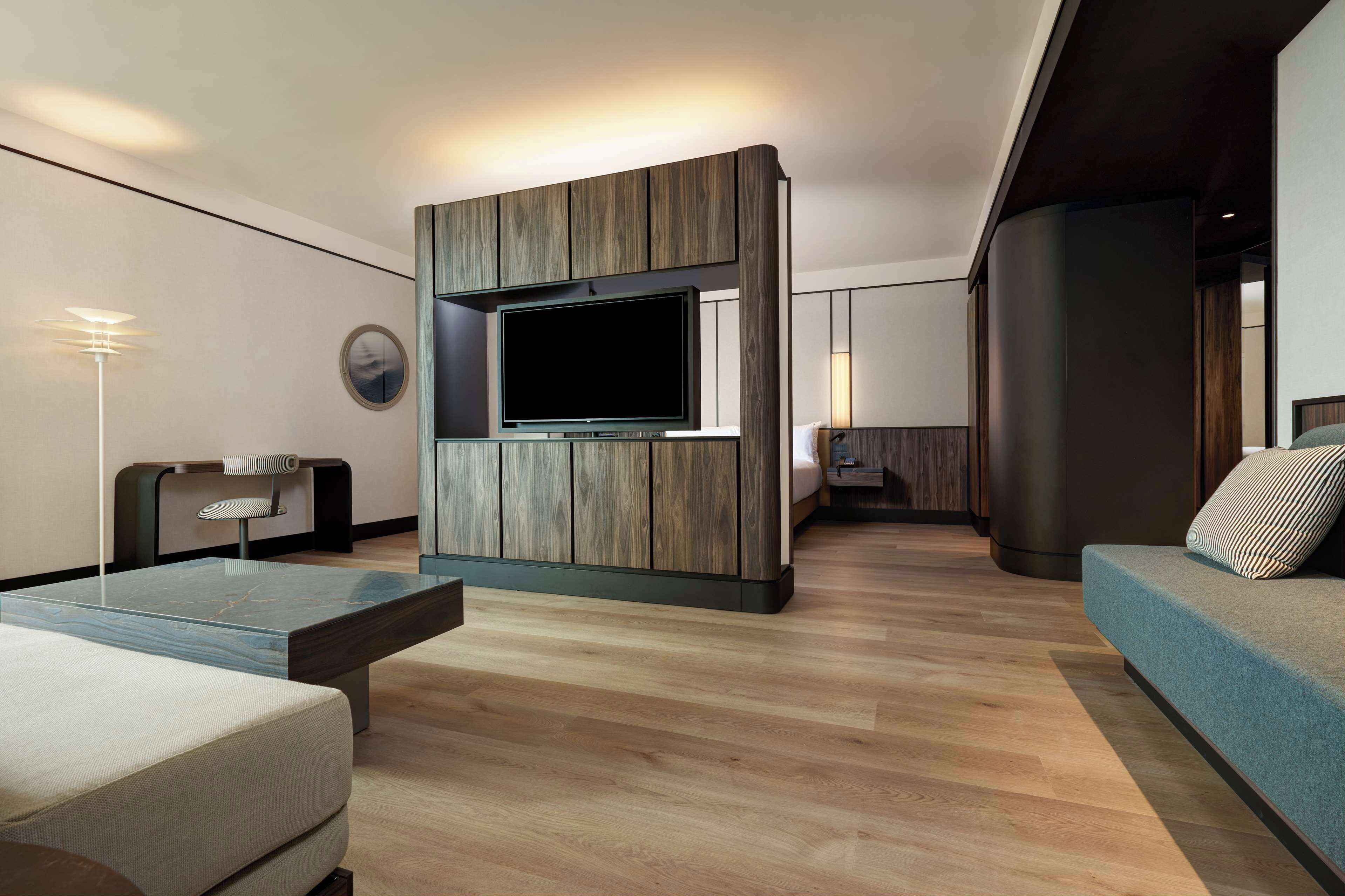 A modern living room with a built-in TV, a sofa, a coffee table, and a floor lamp.