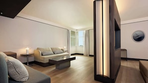 A modern living room with a sofa, a coffee table, a TV, and a side table with a candle.