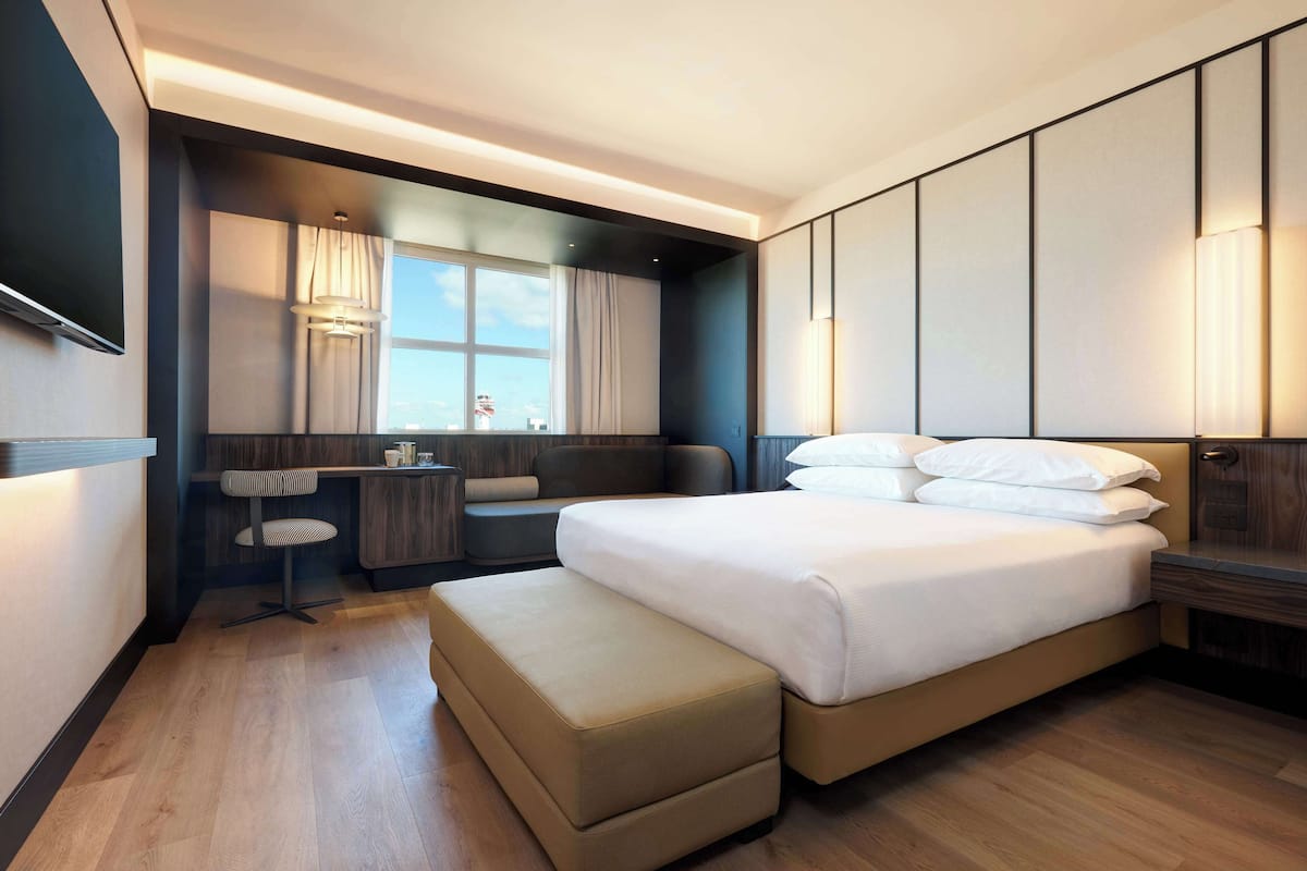 A modern hotel room with a large bed, a desk, and a chair.