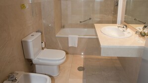 Ein modernes Badezimmer mit Toilette, Bidet, Badewanne und einem großen Spiegel.