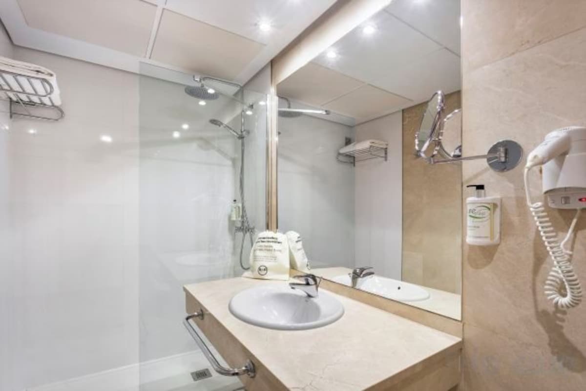 Un baño moderno con lavabo, espejo y ducha.