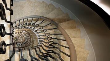 Una escalera de caracol con detalles de mármol y barandilla de metal moderno.