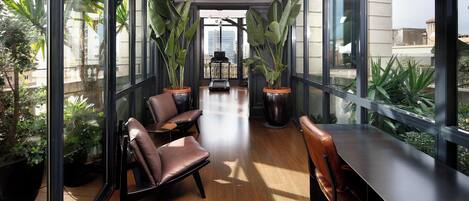 A modern interior with large windows, leather chairs, and potted plants.