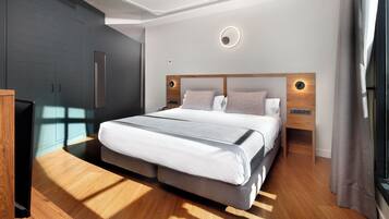 A modern bedroom with a large bed, wooden flooring, built-in wardrobe, and bedside lamps.