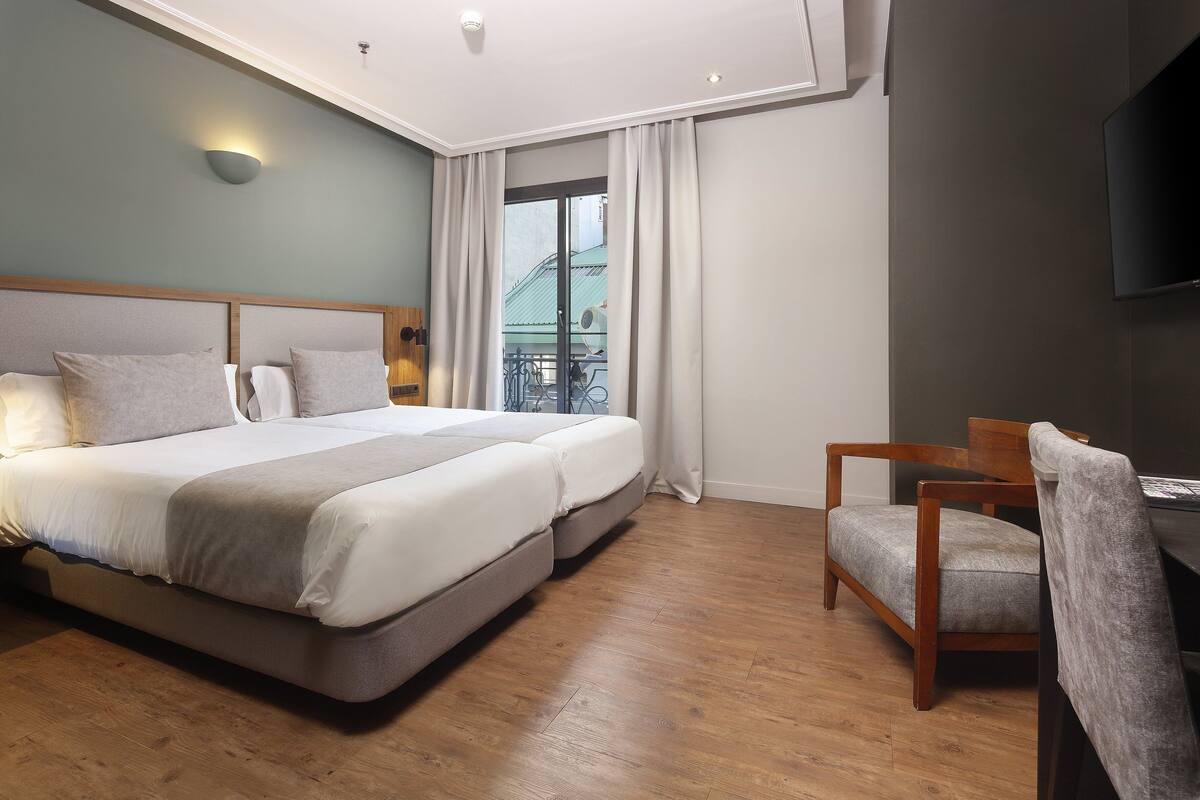 Une chambre d’hôtel avec un grand lit, un bureau et une chaise.