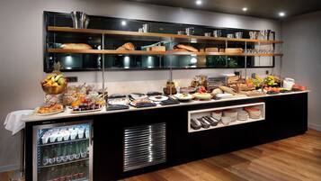 A buffet setup with various food items, a beverage cooler, and shelves with kitchenware.