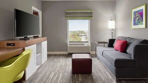 A modern hotel room with a flat-screen TV, a desk, a sofa, a small table, and a window with a view. - Hampton Inn Oklahoma City-I-40 E. (Tinker Air Force Base) (Midwest City)