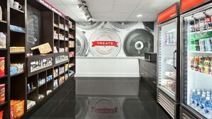 A clean, modern snack bar with shelves stocked with various snacks and beverages, a chalkboard sign, and a refrigerator. - Hampton Inn Oklahoma City-I-40 E. (Tinker Air Force Base) (Midwest City)