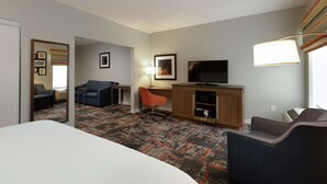 Ein Hotelzimmer mit Bett, Schreibtisch, Fernseher, Stuhl und Teppichboden.