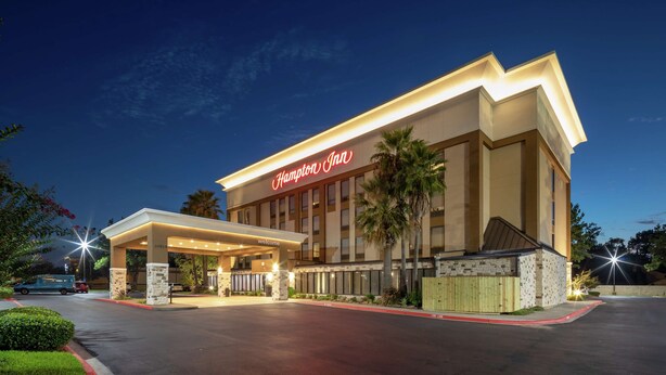 Ein Hampton Inn Hotel mit gut beleuchtetem Eingang, überdachtem Außenbereich und Parkplatz.
