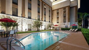 Ein modernes Hotel mit Pool, Sitzgelegenheiten im Freien und einer Steinwand.