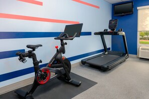 A gym with a stationary bike, a treadmill, and a wall-mounted TV. - Hampton Inn & Suites Austin-Airport (Austin)