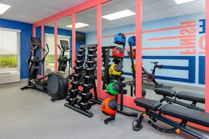 A gym with exercise equipment, a bench, and a wall with motivational text.