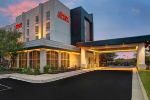 Welcome to Hampton Inn & Suites, featuring a modern entrance surrounded by lush landscaping.