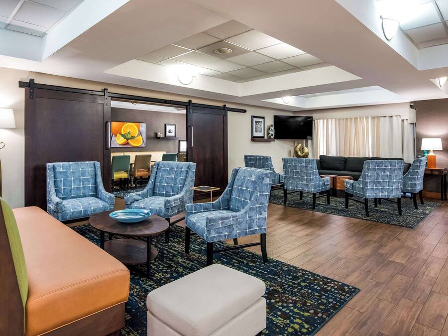 Een hotel lobby met een zithoek, met blauwe gestreepte stoelen, een houten salontafel en een bank.
