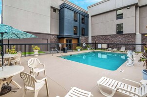 Una piscina al aire libre, sombrillas, sillones reclinables de piscina