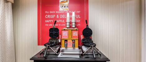 A waffle station with two waffle makers and a sign advertising waffles.